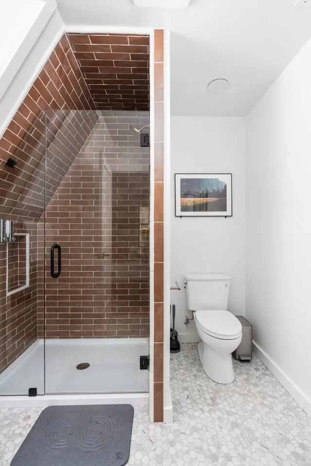 Walk-in shower lined with terracotta tile in the second bathroom